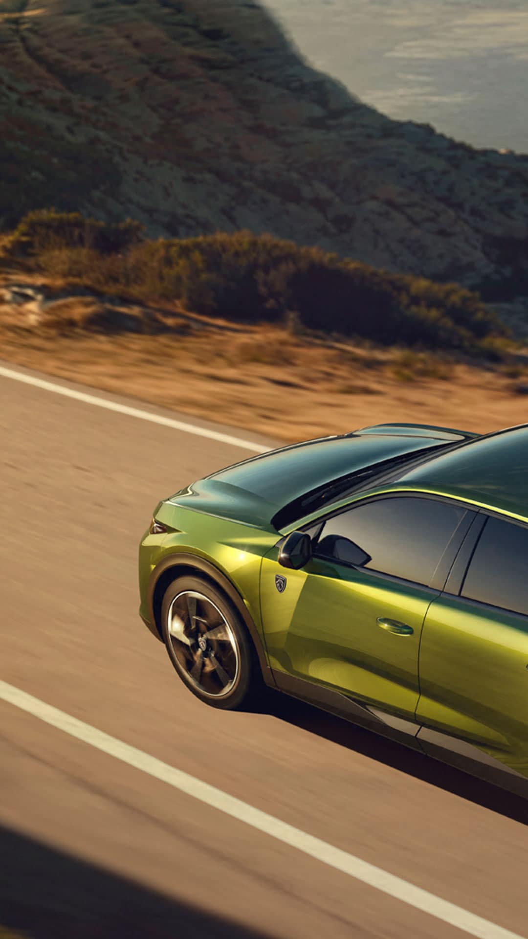 De nieuwe PEUGEOT E-408 op een kustweg langs de zee