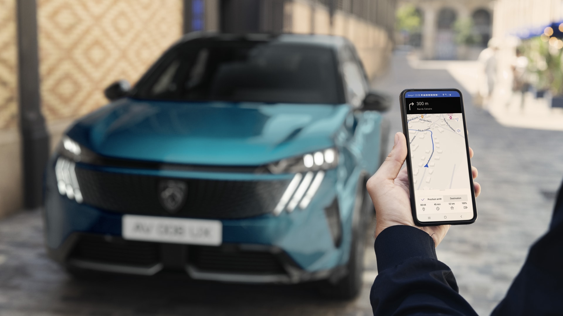 Een man kijkt op zijn smartphone bij de PEUGEOT E-3008