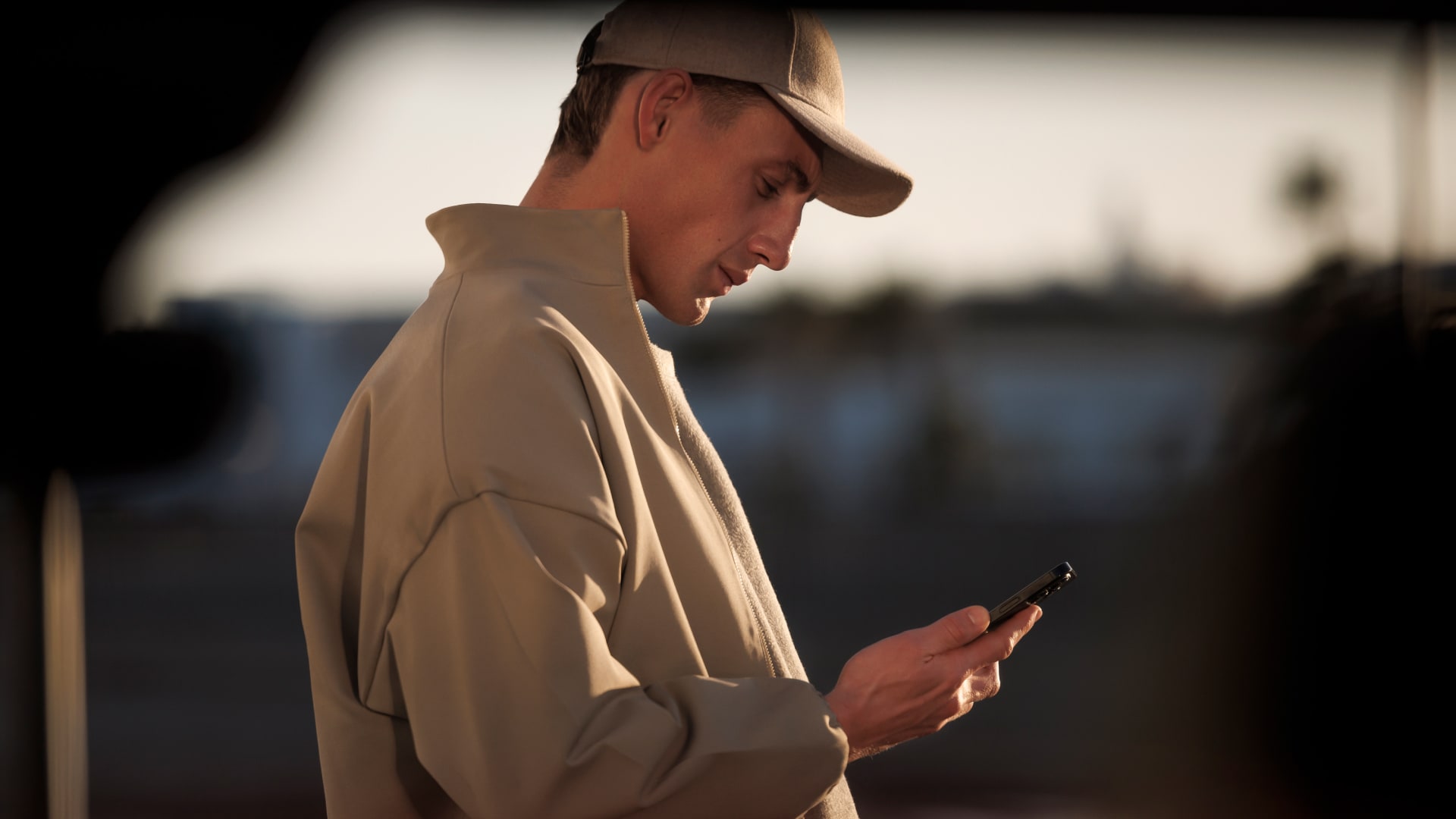 Een man kijkt op zijn smartphone bij de PEUGEOT E-5008