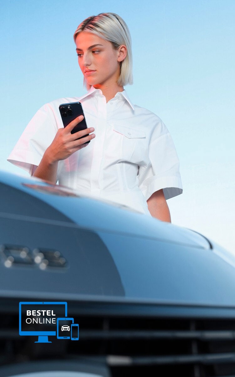 Een vrouw kijkt op haar smartphone naast een Peugeot E-308SW